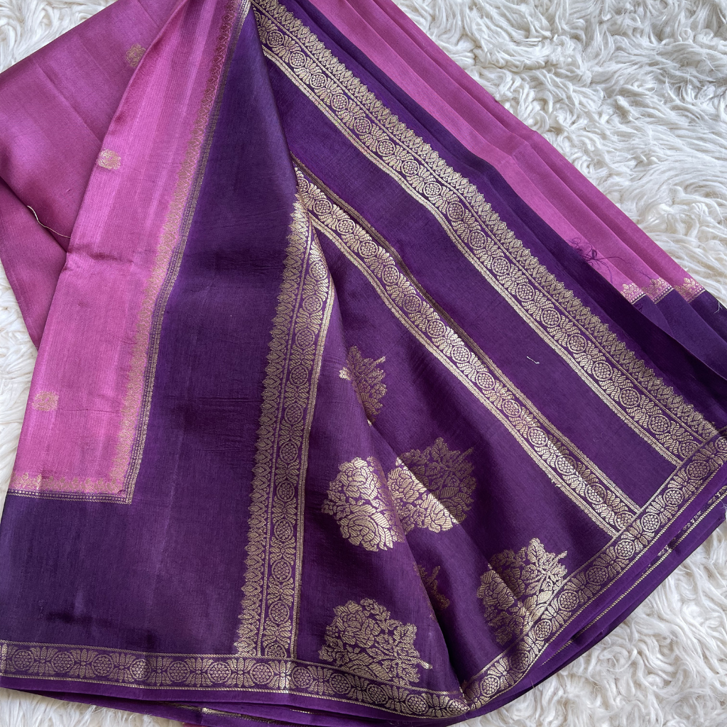Viscous Dola silk Purple saree with gold border on a white textured surface