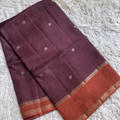 Viscous Dola Silk Chcoloate colored saree with gold patterns and a red border on a white textured background